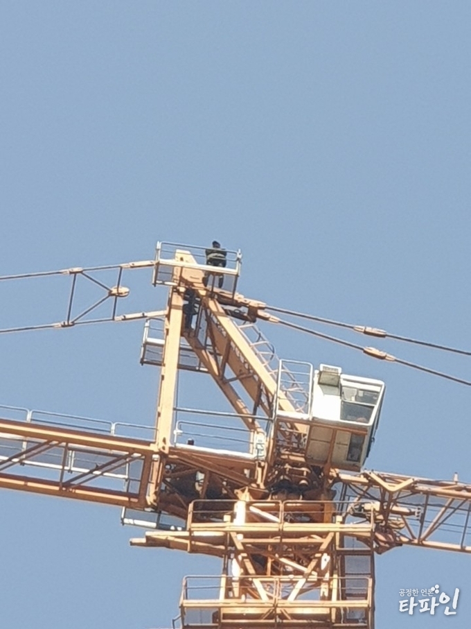 15일 오전 7시 40분께부터 근로자 2명이 전북 군산시 한 아파트 공사현장 25층 높이 타워크레인에 올라 고공농성을 벌이고 있다./사진=전북경찰청