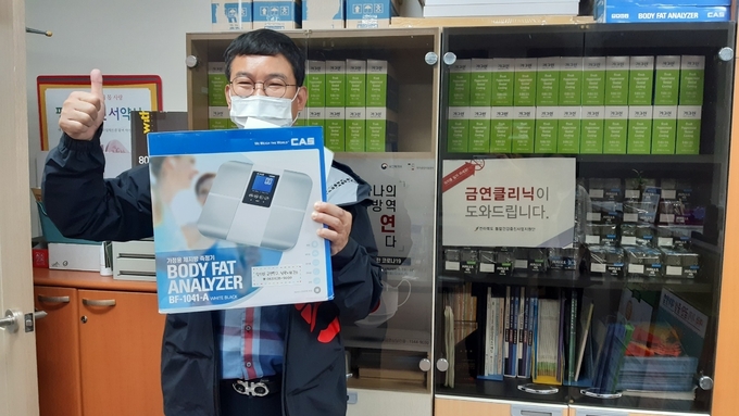 6개월 금연에 성공한 이상선 기자가 사은품을 받고 환하게 웃고 있다. /타파인